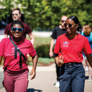 Two students smiling and walking on campus